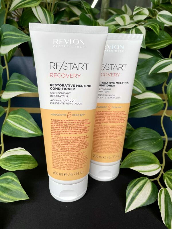 Two tubes of Re/Start Recovery Restorative Melting Conditioner, 200ml each, are displayed with green plants in the background, emphasizing their restorative care for damaged hair. Two tubes of Re/Start Recovery Restorative Melting Conditioner, 200ml each, are displayed with green plants in the background, emphasizing their restorative care for damaged hair.