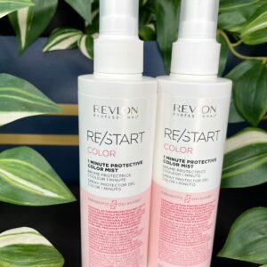 Two bottles of Re/Start Color 1 Minute Protective Mist (200 ml each) for color-treated hair are displayed with a backdrop of green and white plants.
