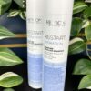 Two white bottles of Re/Start Hydration Moisture Micellar Shampoo, 250 ml each, are showcased in front of vibrant green foliage.