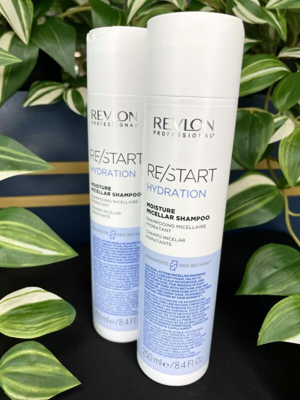 Two white bottles of Re/Start Hydration Moisture Micellar Shampoo, 250 ml each, are showcased in front of vibrant green foliage. Two white bottles of Re/Start Hydration Moisture Micellar Shampoo, 250 ml each, are showcased in front of vibrant green foliage.