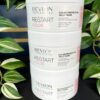 Three stacked containers of the Re/Start Color Protective Jelly Mask are displayed in front of lush green plants, highlighting this nourishing mask’s sleek, color-protective formula.