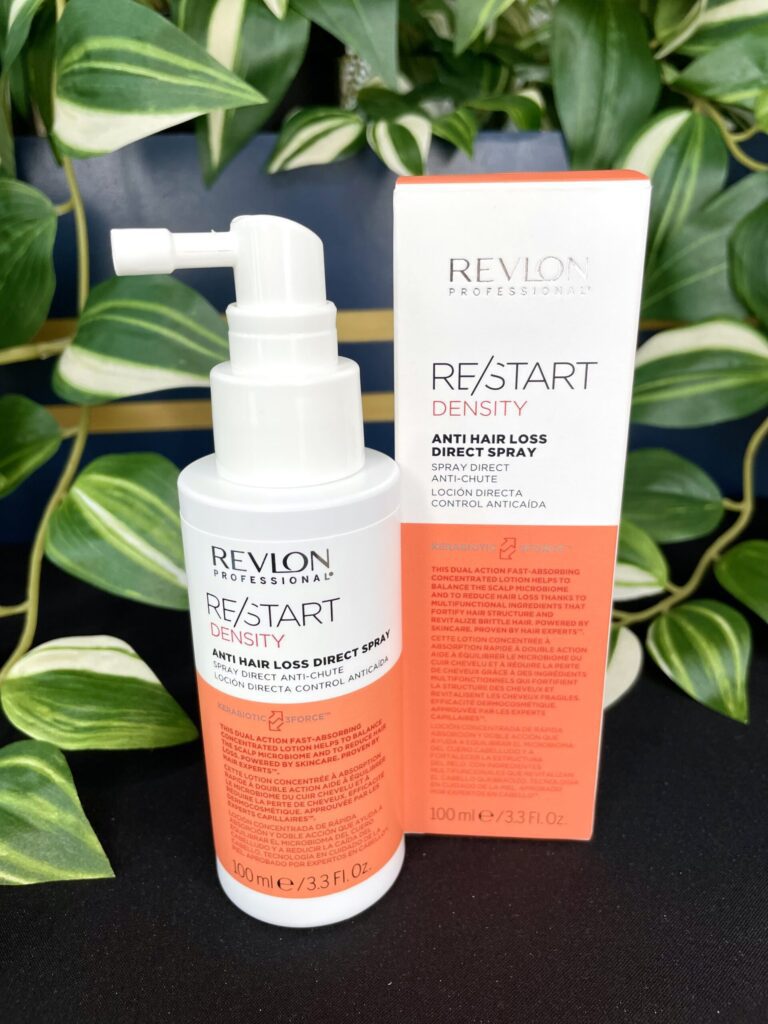 A Re/Start Density Anti Hair Loss Direct Spray bottle is shown beside its packaging, with green leaves in the background.