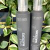 Two upright Style Masters Modular Mousse 300ml bottles are shown on a black surface, with green leafy plants in the background.