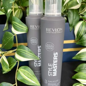 Two bottles of Style Masters Pure Styler Hairspray 325ml in gray stand upright among green leafy plants.