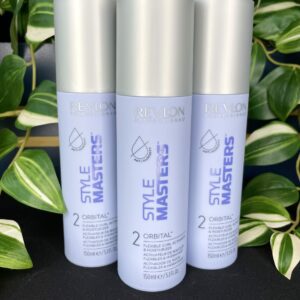 Three bottles of Style Masters Orbital Curl Activator 150ml are displayed upright in front of vibrant green leafy plants.