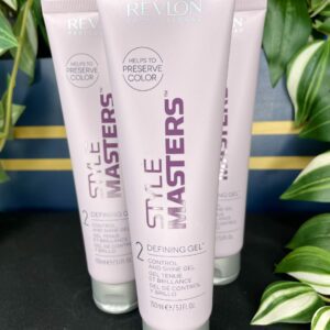 Three tubes of Style Masters Defining Gel 150ml stand upright among lush green plants.
