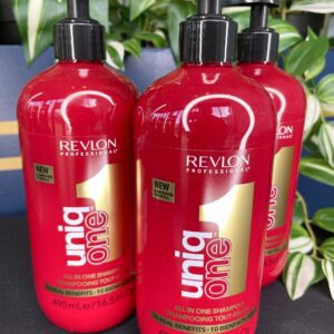 Three bottles of UniqOne All in One Shampoo 490ml are shown with green plants in the background.