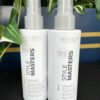 Two bottles of Style Masters Lissaver Heat Protection Spray 150ml are displayed on a black surface, with green and white leafy plants in the background.