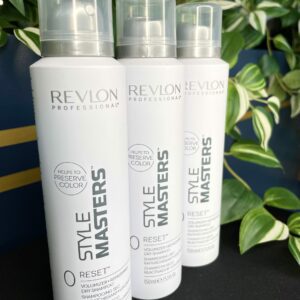 Three bottles of Style Masters Reset Dry Shampoo 150ml are displayed upright with green plants in the background.
