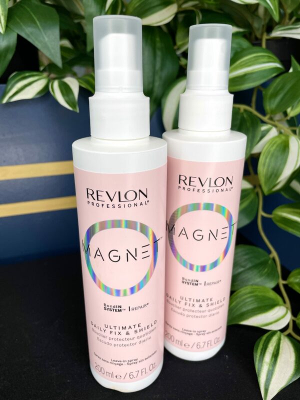 Two bottles of Revlon Magnet Ultimate Daily Fix and Shield Spray 200ml are displayed in front of green variegated leaves. Two bottles of Revlon Magnet Ultimate Daily Fix and Shield Spray 200ml are displayed in front of green variegated leaves.