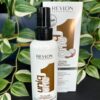 A bottle of UniqOne All in One Hair Treatment Coconut 150ml stands before its packaging, set against green leaves in the background.